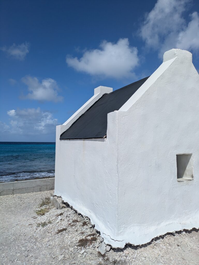 A white washed small building on a beach.
